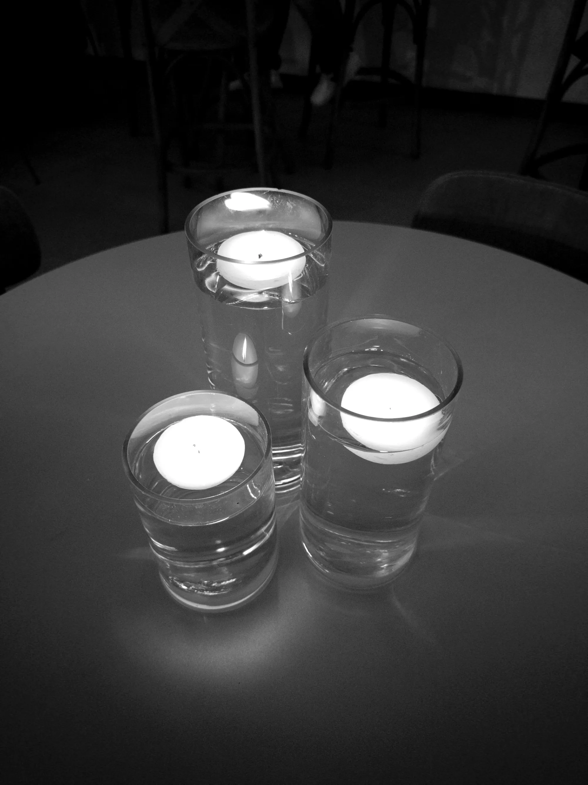 Velas acesas em taças sobre mesa, detalhe de ambientação de um evento da Filarmônica Aruna
