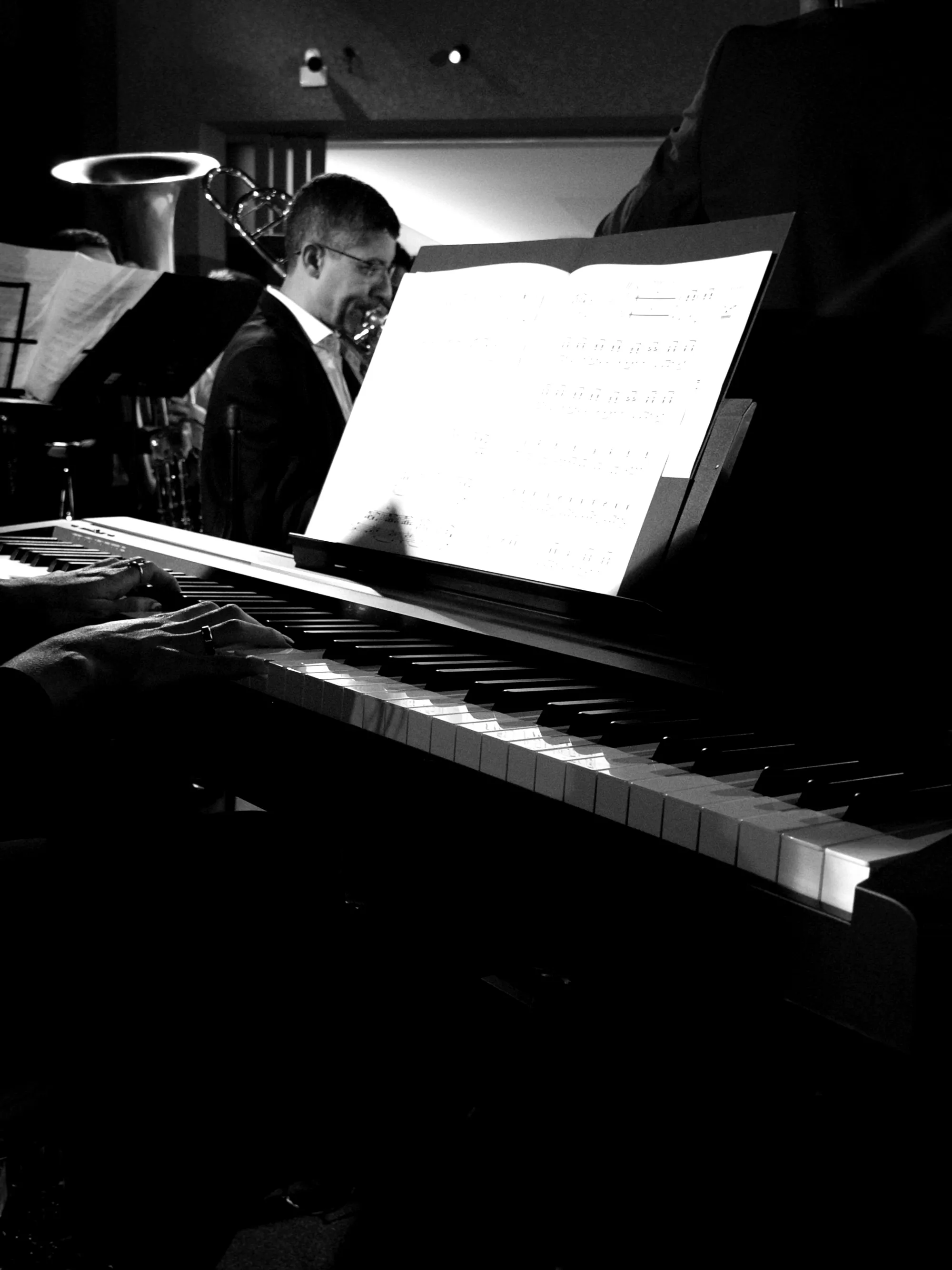 Mãos de pianista da Filarmônica Aruna sobre o teclado, partitura aberta no estande